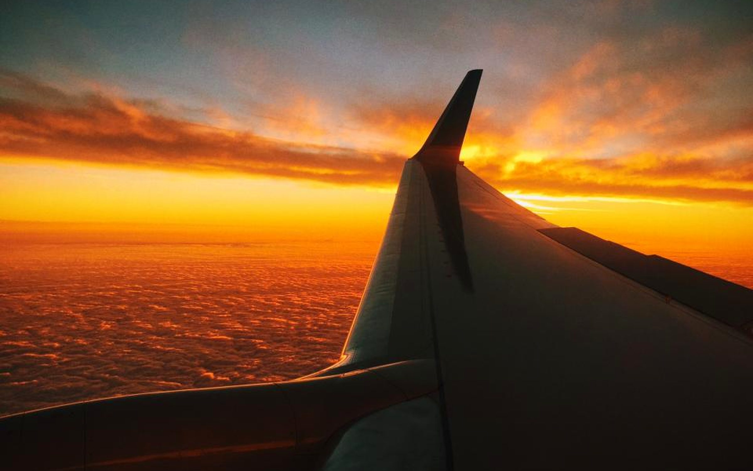 Ala de avión sobre un mar de nubes al atardecer